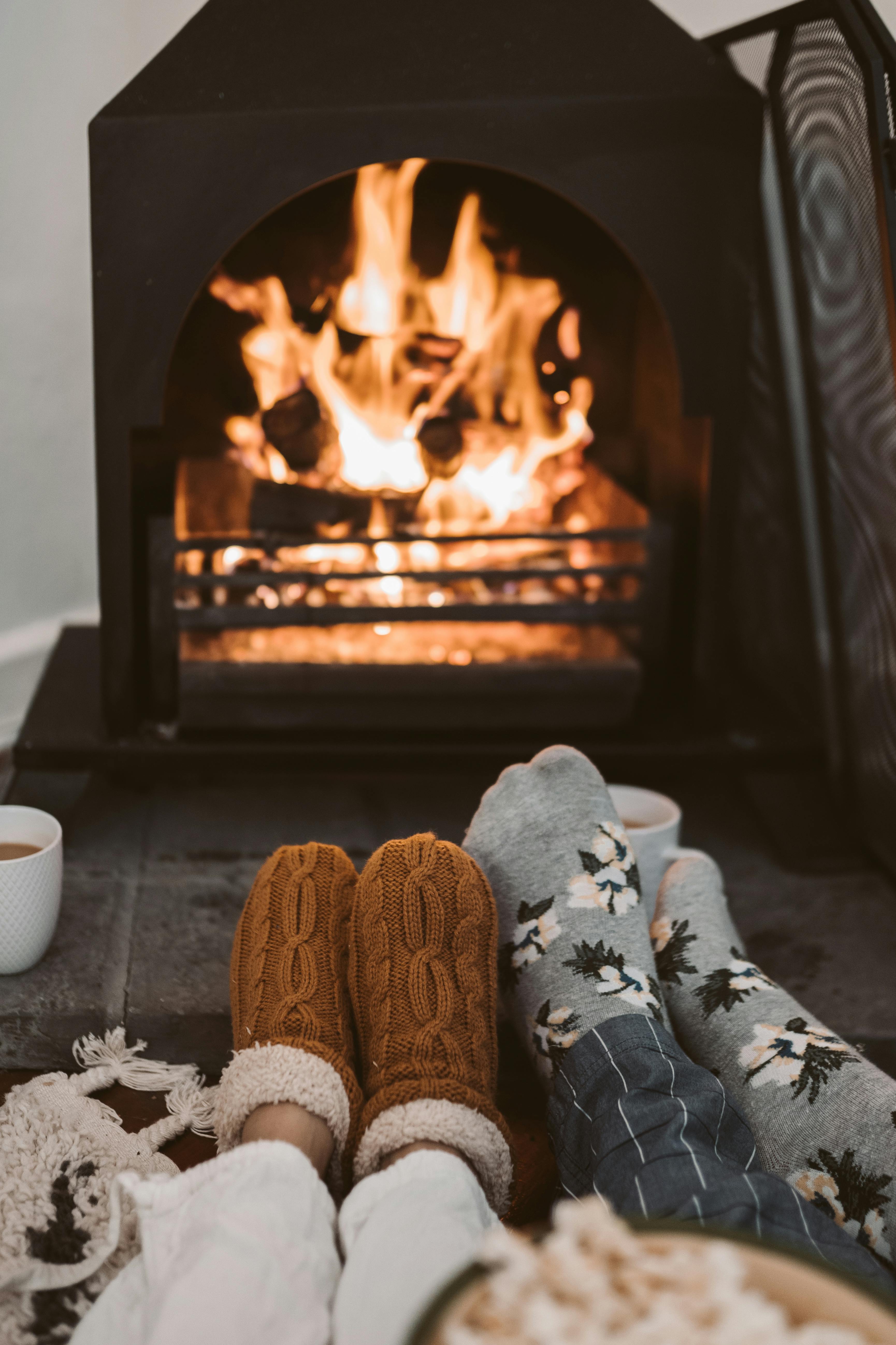 Two people warm by a fireplace